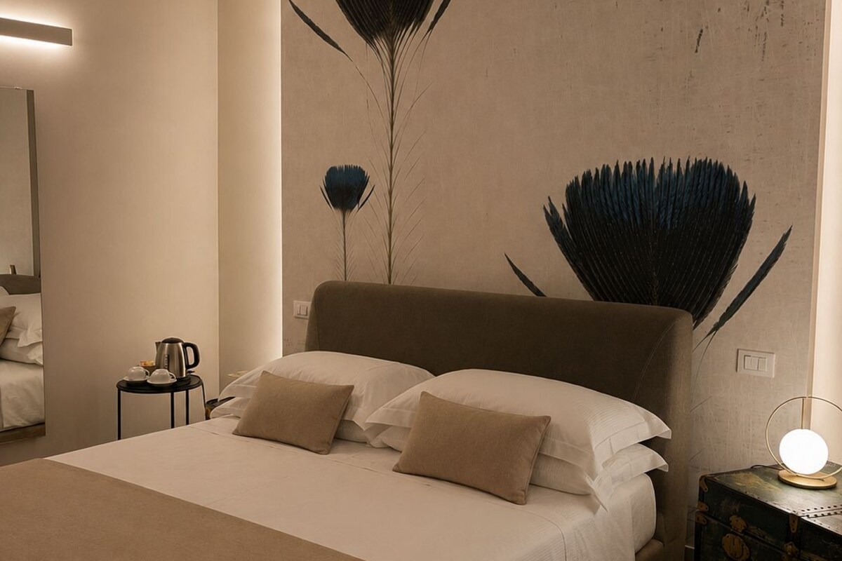 Une chambre à coucher moderne avec un grand lit, une table de chevet avec une lampe et un miroir fixé au mur.