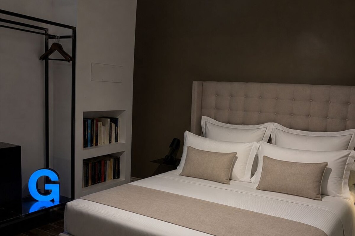 Une chambre avec un grand lit, une bibliothèque et un portant à vêtements.