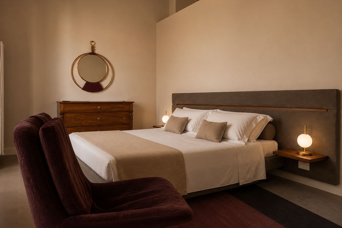 Une chambre à coucher avec un lit, une commode en bois, un miroir rond et deux lampes de chevet.