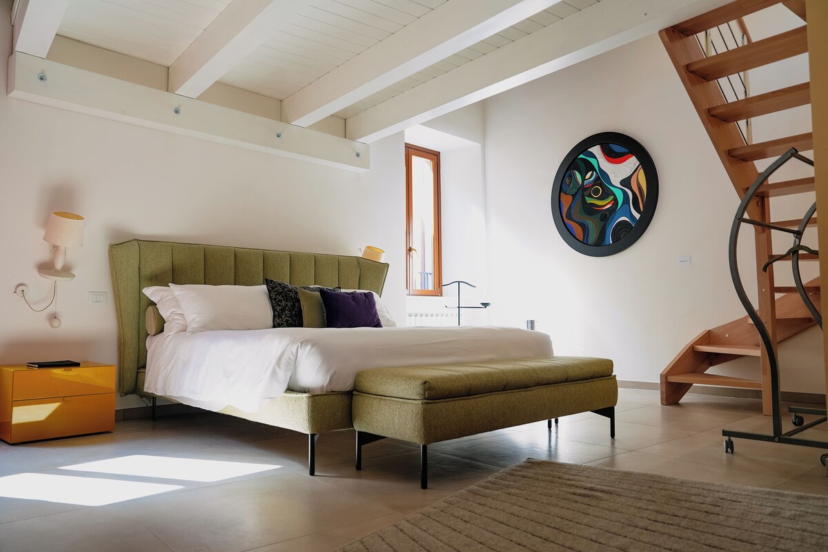 Une chambre à coucher avec un lit, une table de chevet, une lampe et un tableau au mur.