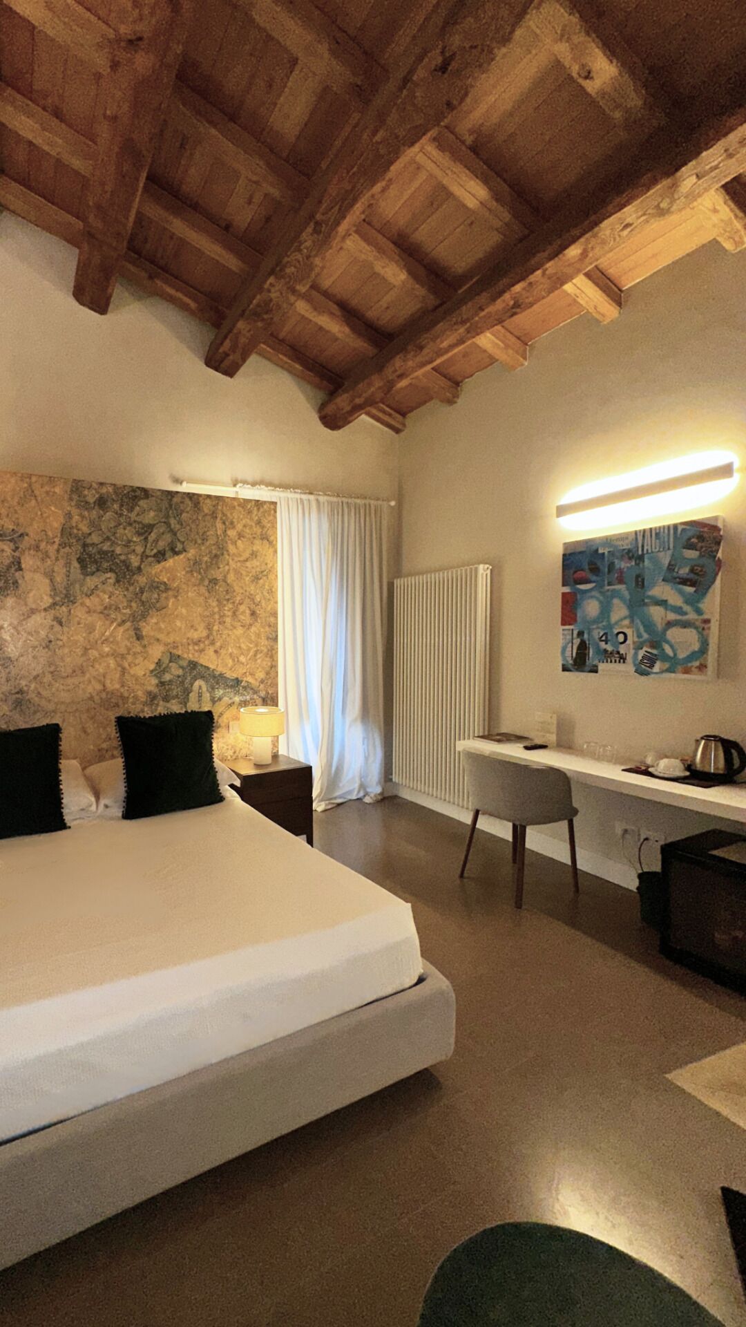 Un dormitorio con una cama grande, un escritorio, una silla, un radiador y una pared con un cartel.