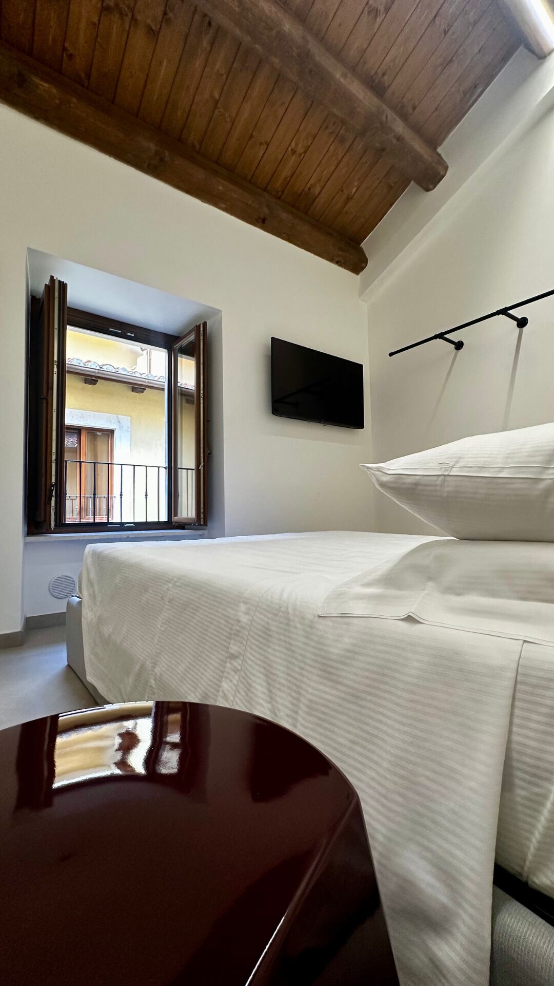 Ein Schlafzimmer mit einem Bett, einem Fernseher und einem Fenster mit Blick auf einen Balkon.