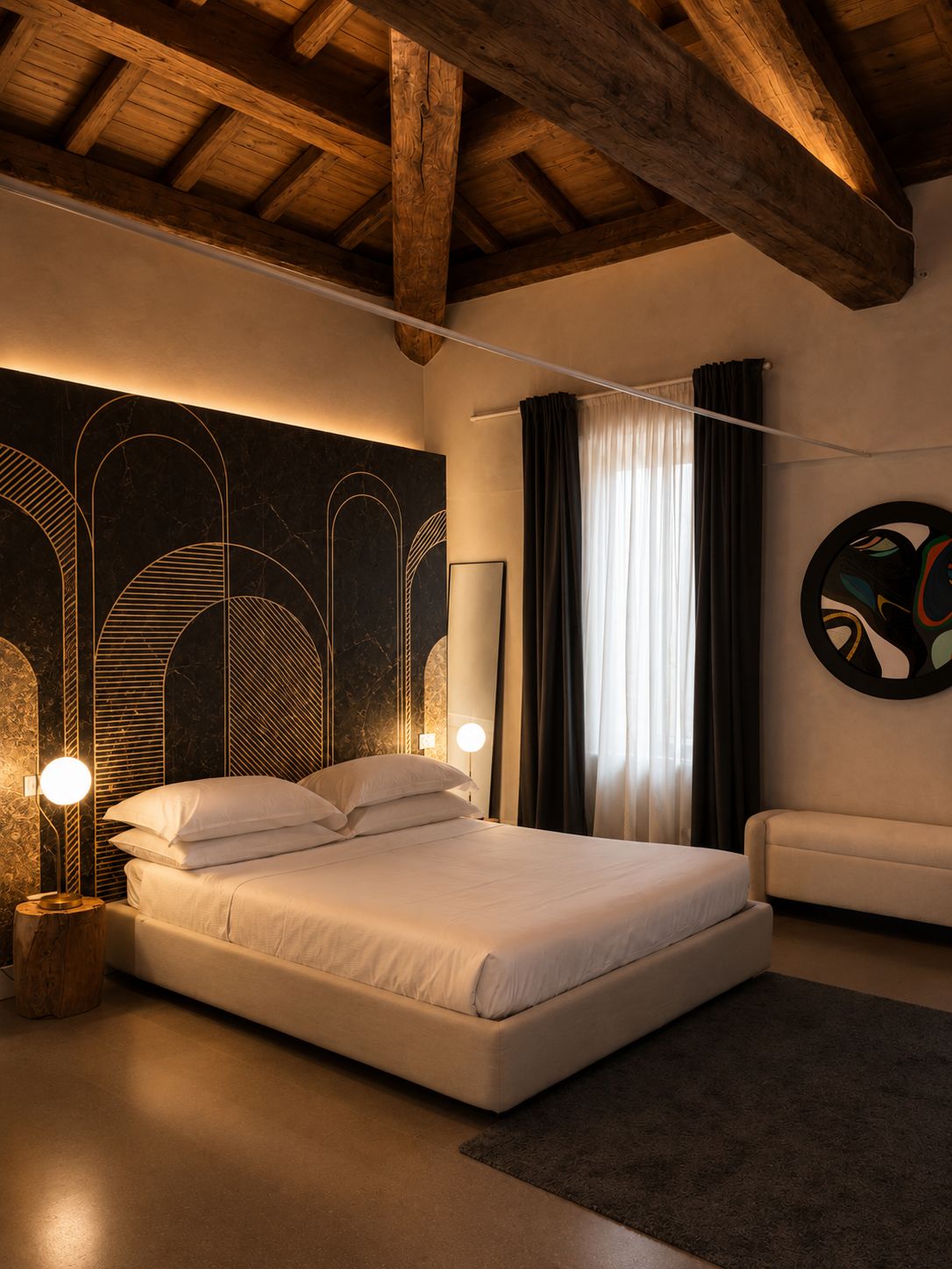 Une chambre moderne avec un grand lit, un plafond en bois et un mur orné d’œuvres d’art abstraites.