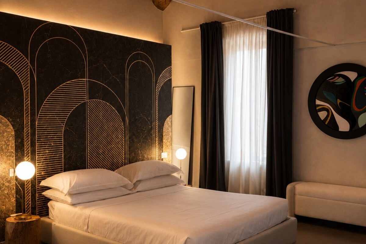 Une chambre moderne avec un grand lit, un plafond en bois et un mur orné d’œuvres d’art abstraites.