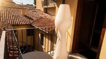 Ein Balkon mit rundem Tisch, einem Stuhl und einer großen weißen Vase.
