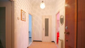 Un couloir avec une porte, un radiateur et un luminaire.