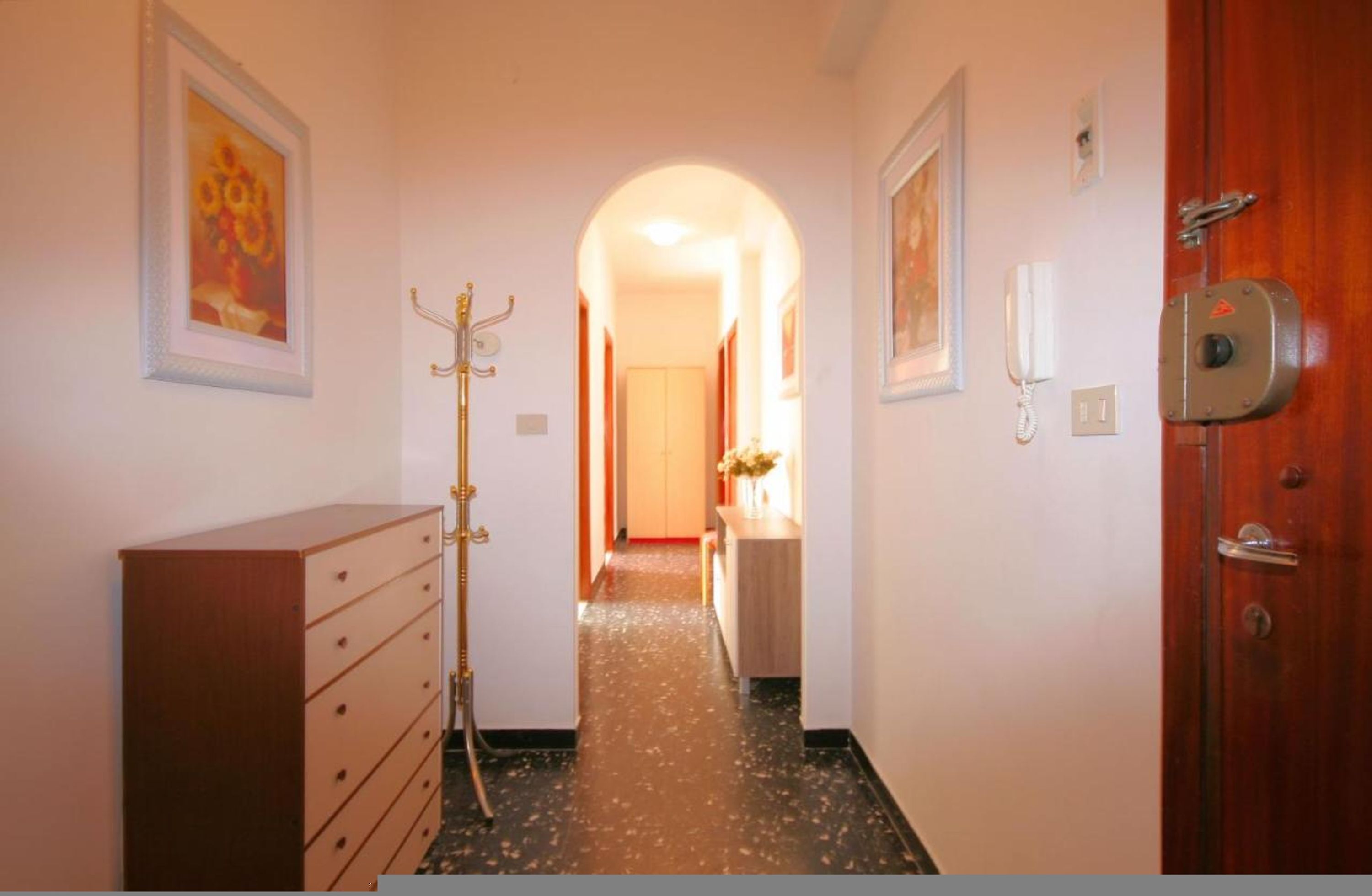 A hallway with a wooden dresser, coat rack, and a door with a security lock.