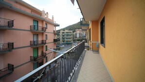 Varanda com grade de metal vista para uma rua com edifícios.