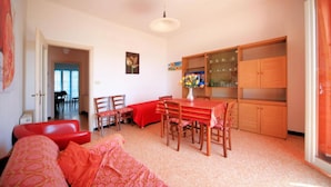 A dining area with a table and chairs, a red sofa, and a cabinet with glass doors. - Doria 6 Int 5 in Marina di Andora (Andora)