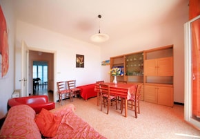 A dining area with a table and chairs, a red sofa, and a cabinet with glass doors.
