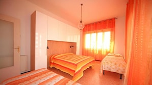 A bedroom with two beds, a wardrobe, a bedside table, and a window with curtains. - Doria 6 Int 5 in Marina di Andora (Andora)