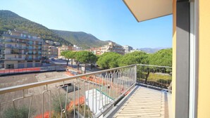 A balcony with a view of a residential area, including multi-story buildings and a hilly landscape.