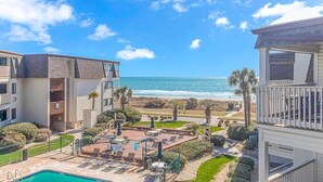 A beachfront hotel with a pool, lounge chairs, and a view of the ocean. - Ocean Forest Villas A-305 (Myrtle Beach)