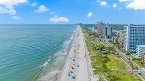 A coastal cityscape with a beach, high-rise buildings, and a clear sky. - Ocean Forest Villas A-305 (Myrtle Beach)
