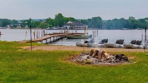 A lakeside dock with canoes, a grassy area, and a building in the background.