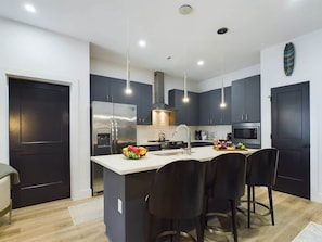 A modern kitchen with dark cabinets, stainless steel appliances, and a central island with bar stools.