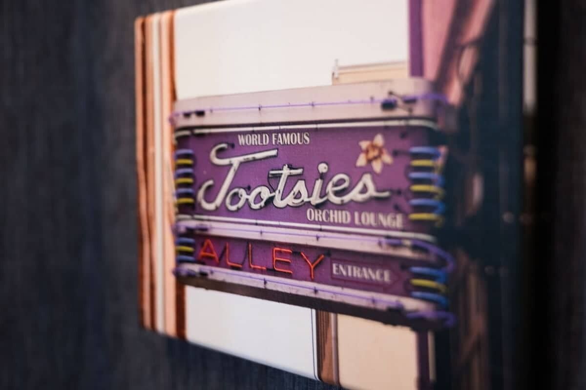 Un letrero de neón antiguo para 'Tootsies Orchid Lounge' con la inscripción 'Famoso en todo el mundo' y 'Entrada al callejón'.
