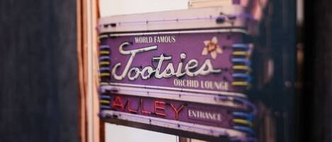 Un letrero de neón antiguo para 'Tootsies Orchid Lounge' con la inscripción 'Famoso en todo el mundo' y 'Entrada al callejón'.
