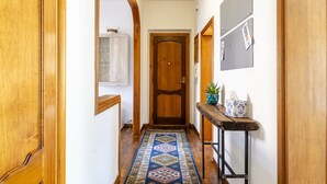 A hallway with wooden doors, a patterned rug, a small table with a plant, and a cabinet. - GuestHost - Hospital Riuniti - Lovely Apartment with Parking! (Livorno)
