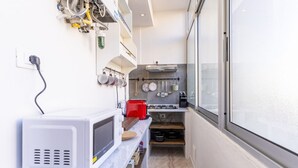 A narrow kitchen with a microwave, a red toaster, and a window. - GuestHost - Hospital Riuniti - Lovely Apartment with Parking! (Livorno)