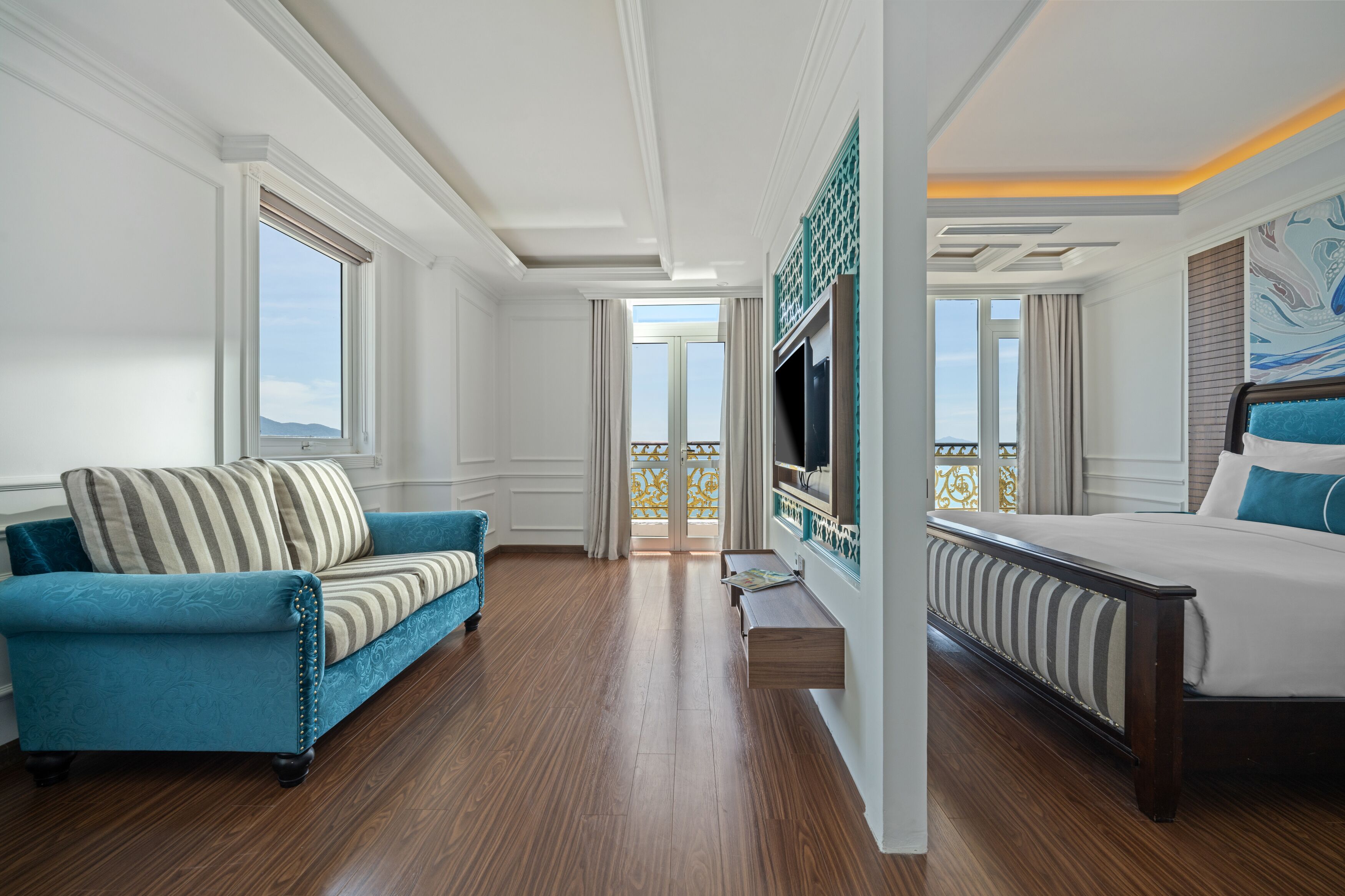 Une chambre d’hôtel avec un canapé, un lit, une télévision et un balcon offrant une vue.