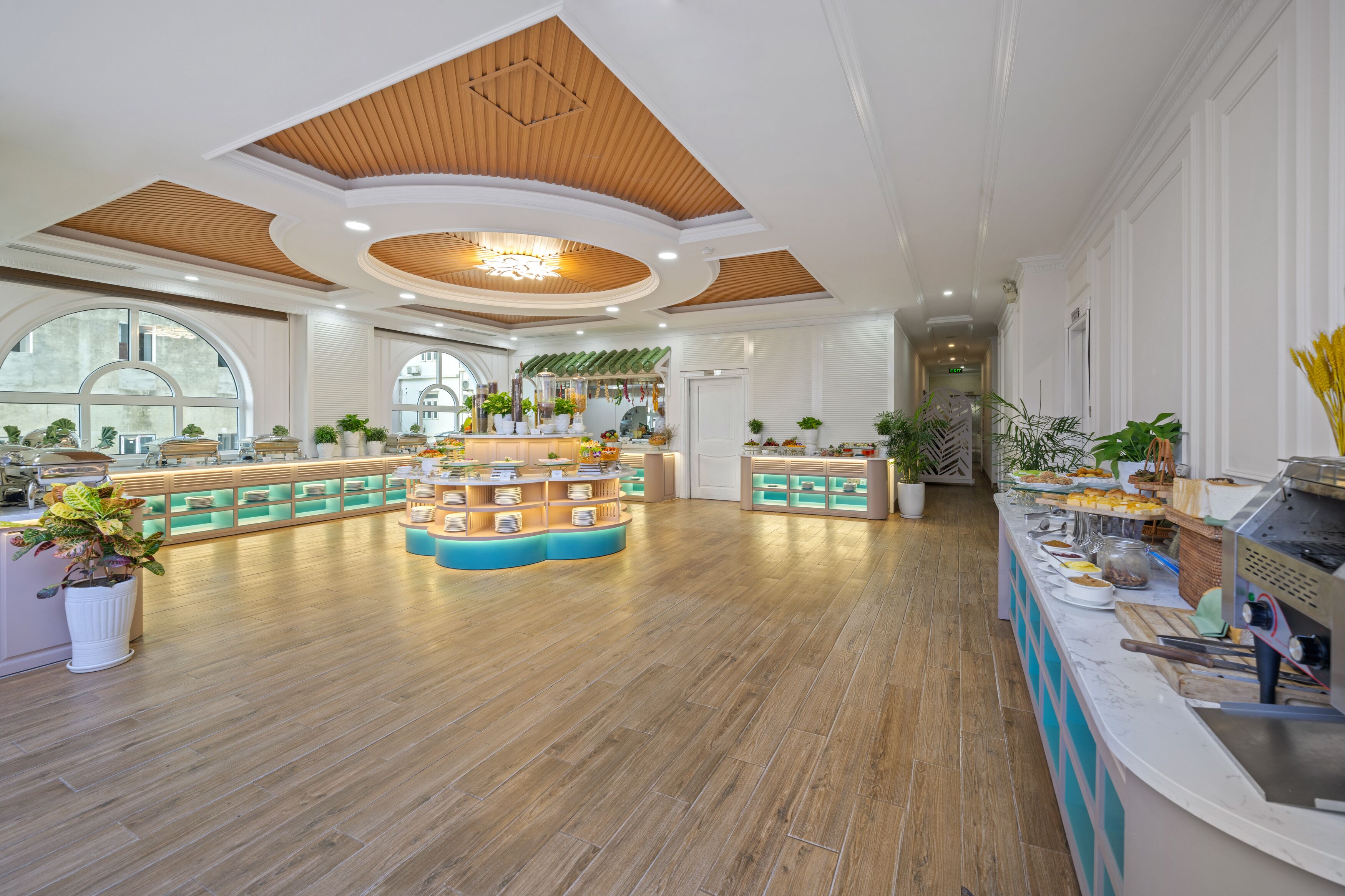 Un hall d’entrée spacieux doté d’un plancher en bois, d’un îlot central avec des sièges et d’une variété de plantes.