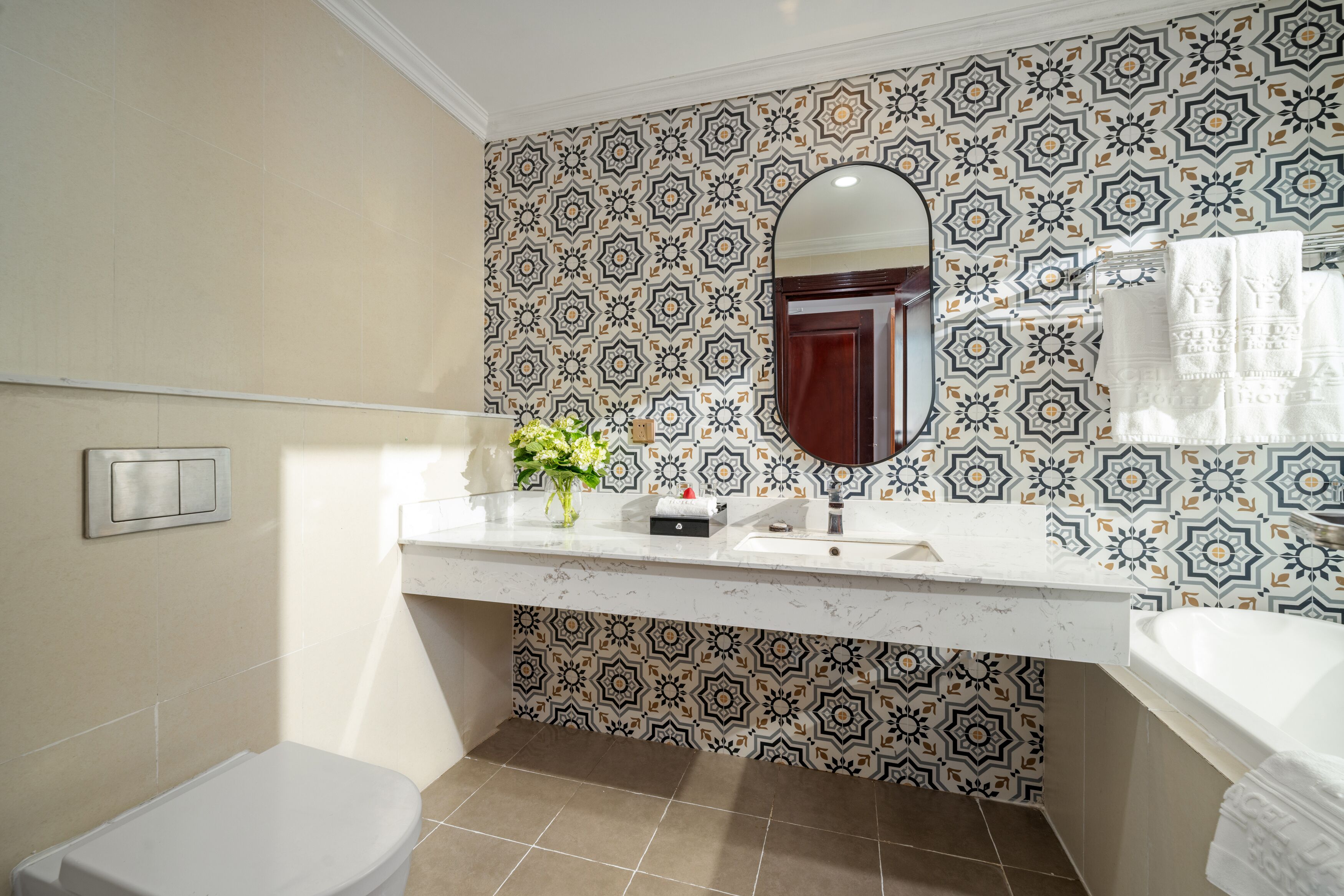 A bathroom with patterned tiles, a white sink, a mirror, and a toilet.