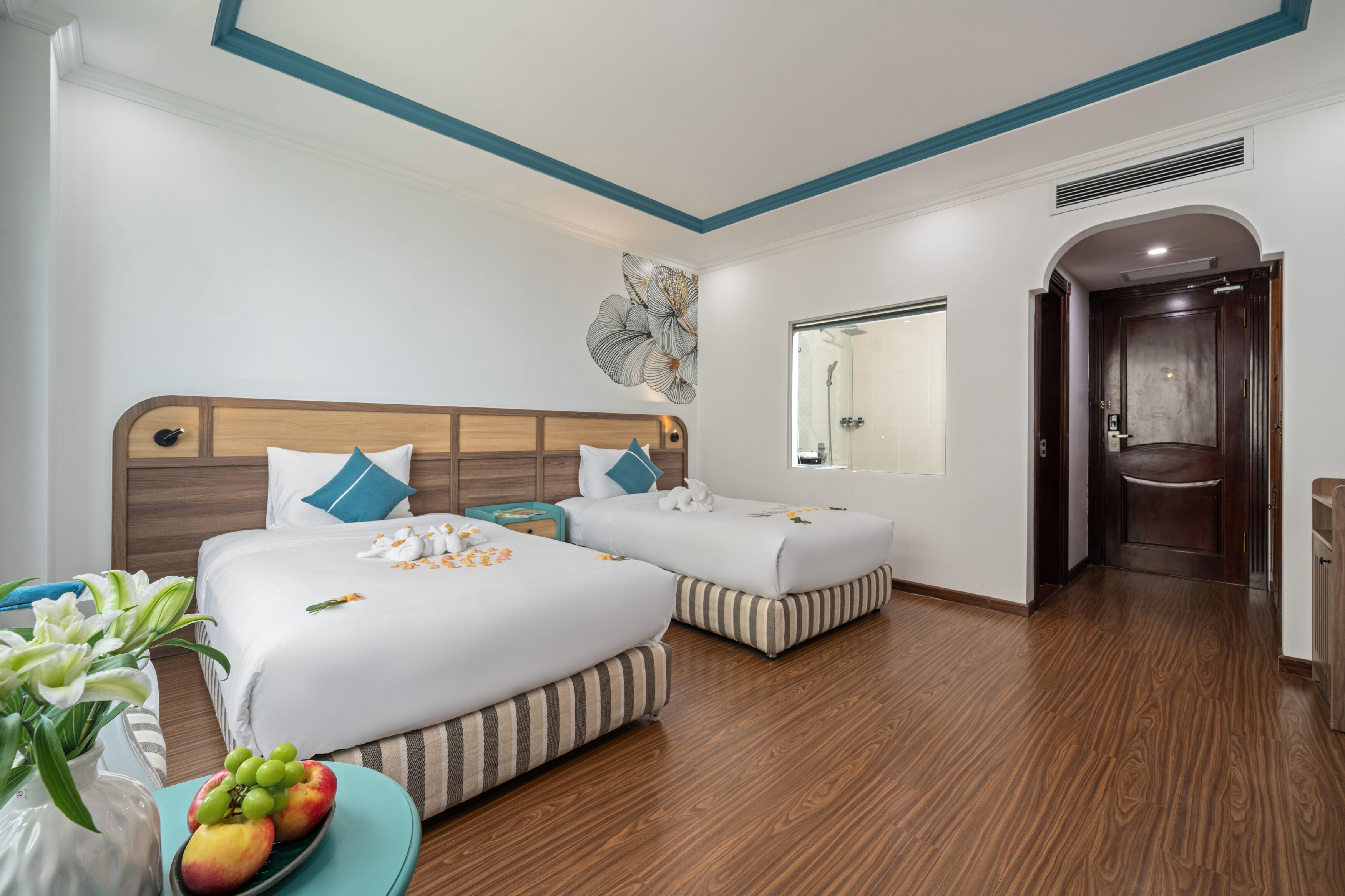 A hotel room with two beds, a large mirror, and a wooden floor.