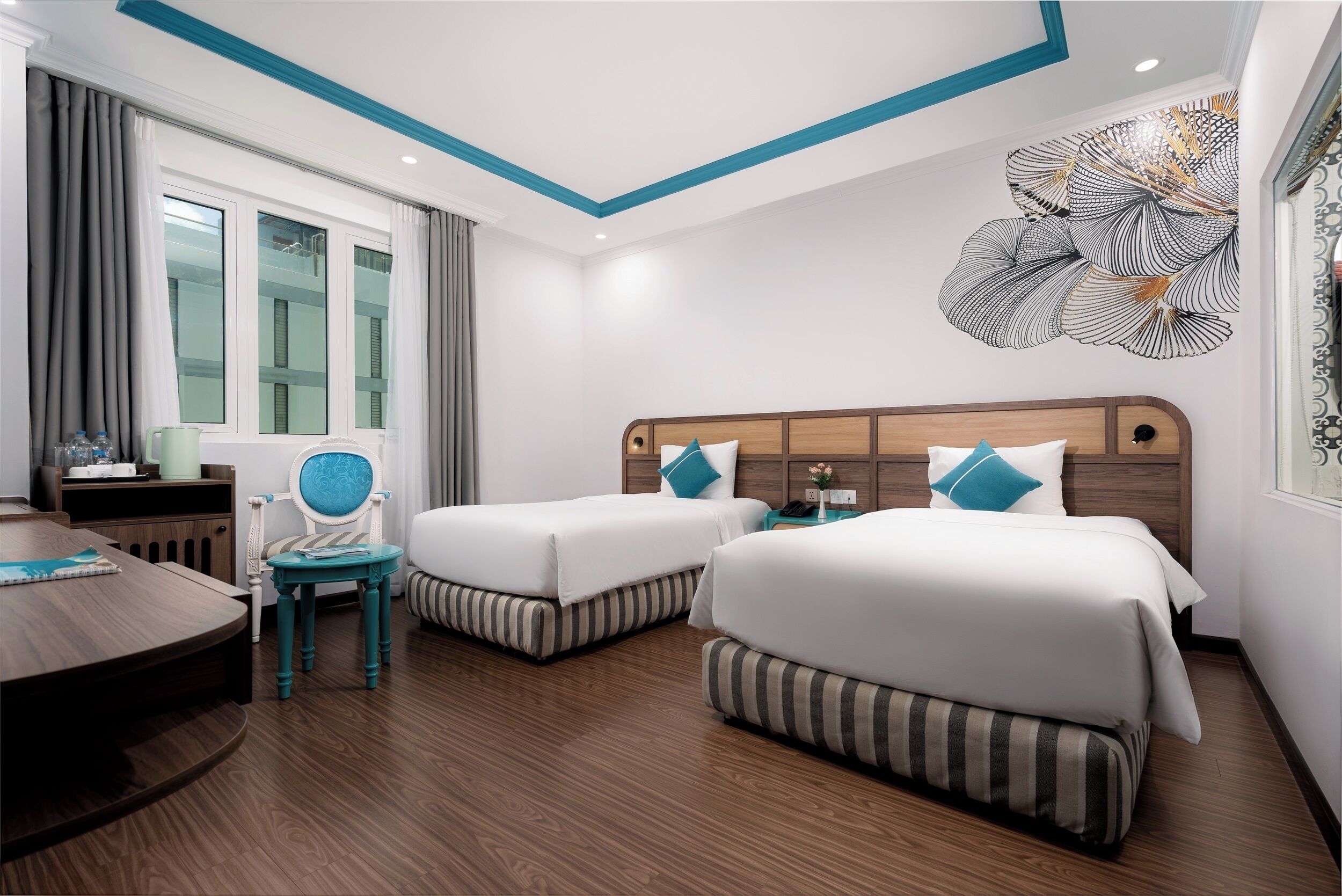 Ein Hotelzimmer mit zwei Betten, einem Holztisch, einem Stuhl, einem Tisch und einer großen Wanddekoration.