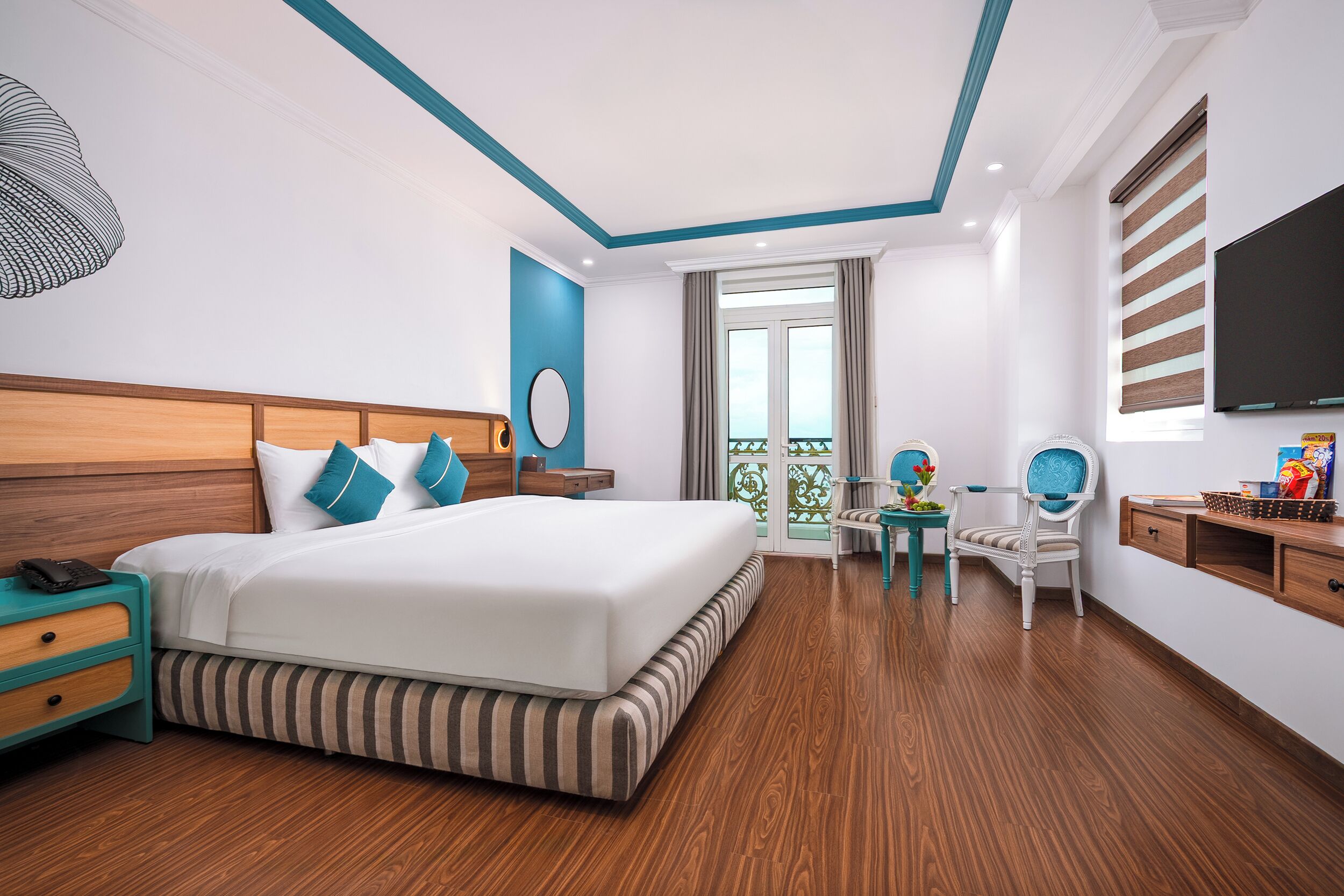 A modern hotel room with a large bed, wooden nightstands, a desk, and a TV.