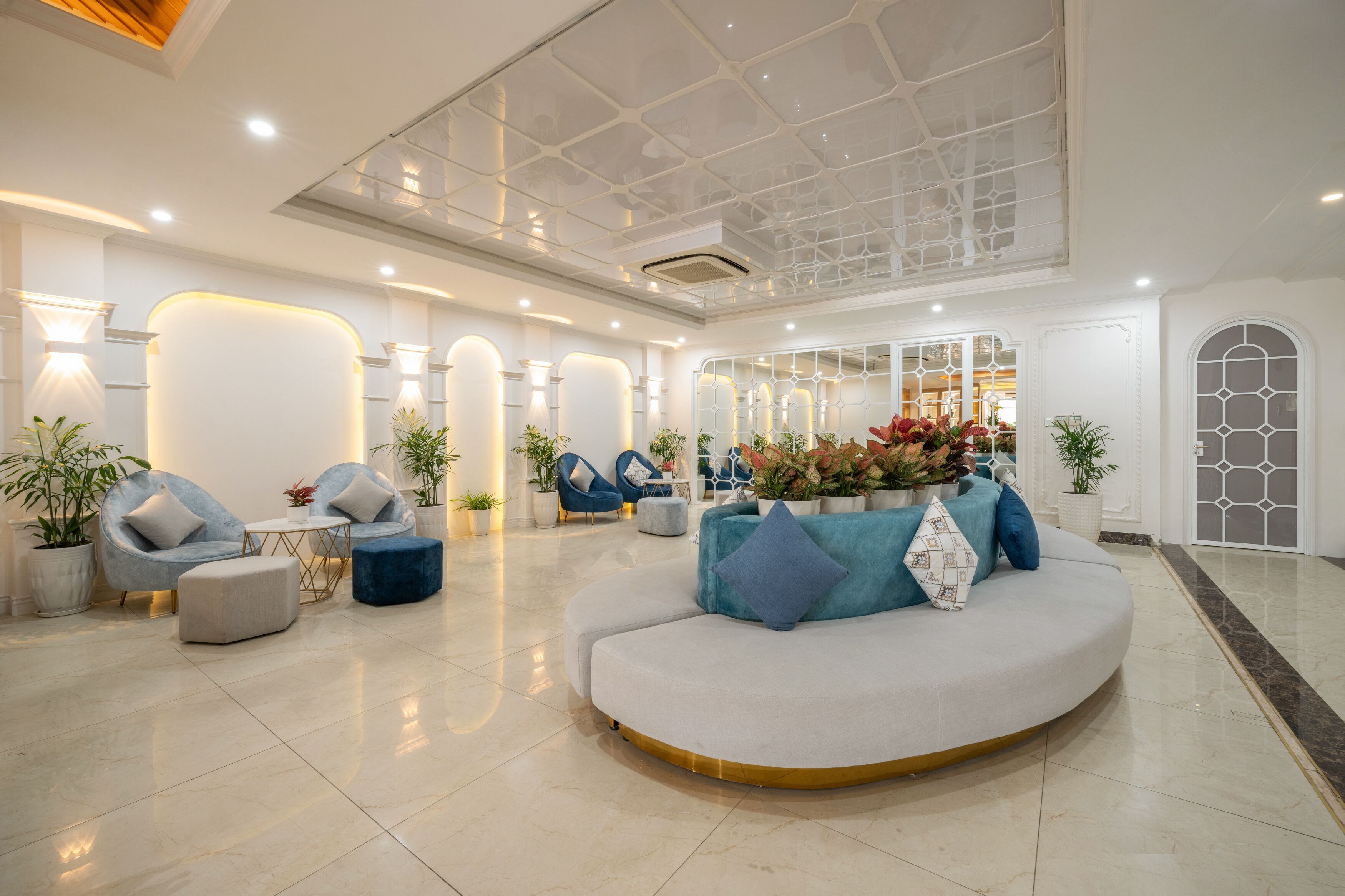 A modern lobby with a curved seating area, potted plants, and a glass ceiling.