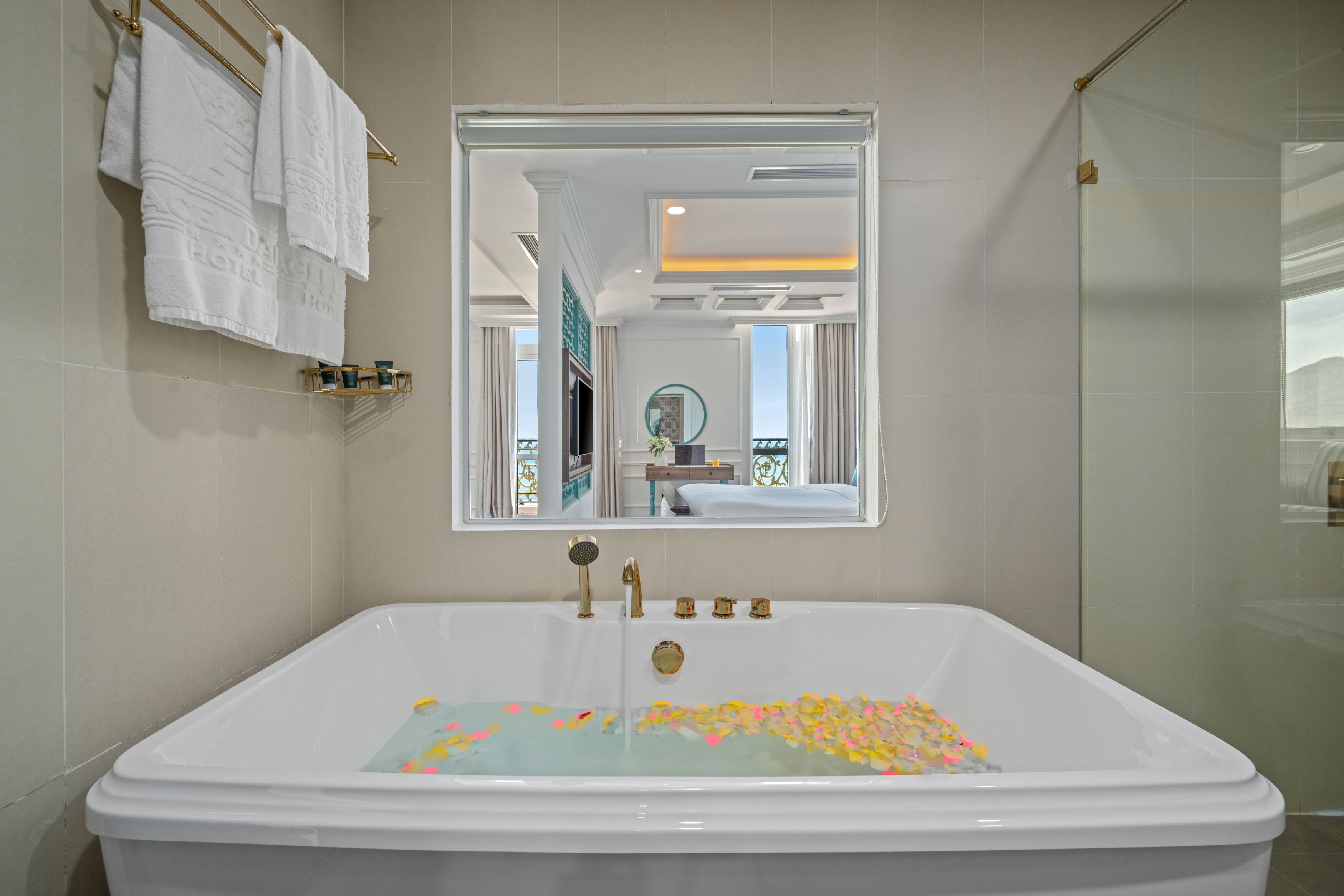 Une salle de bain avec une baignoire remplie de pétales de rose, un robinet doré et un miroir au-dessus de la baignoire.