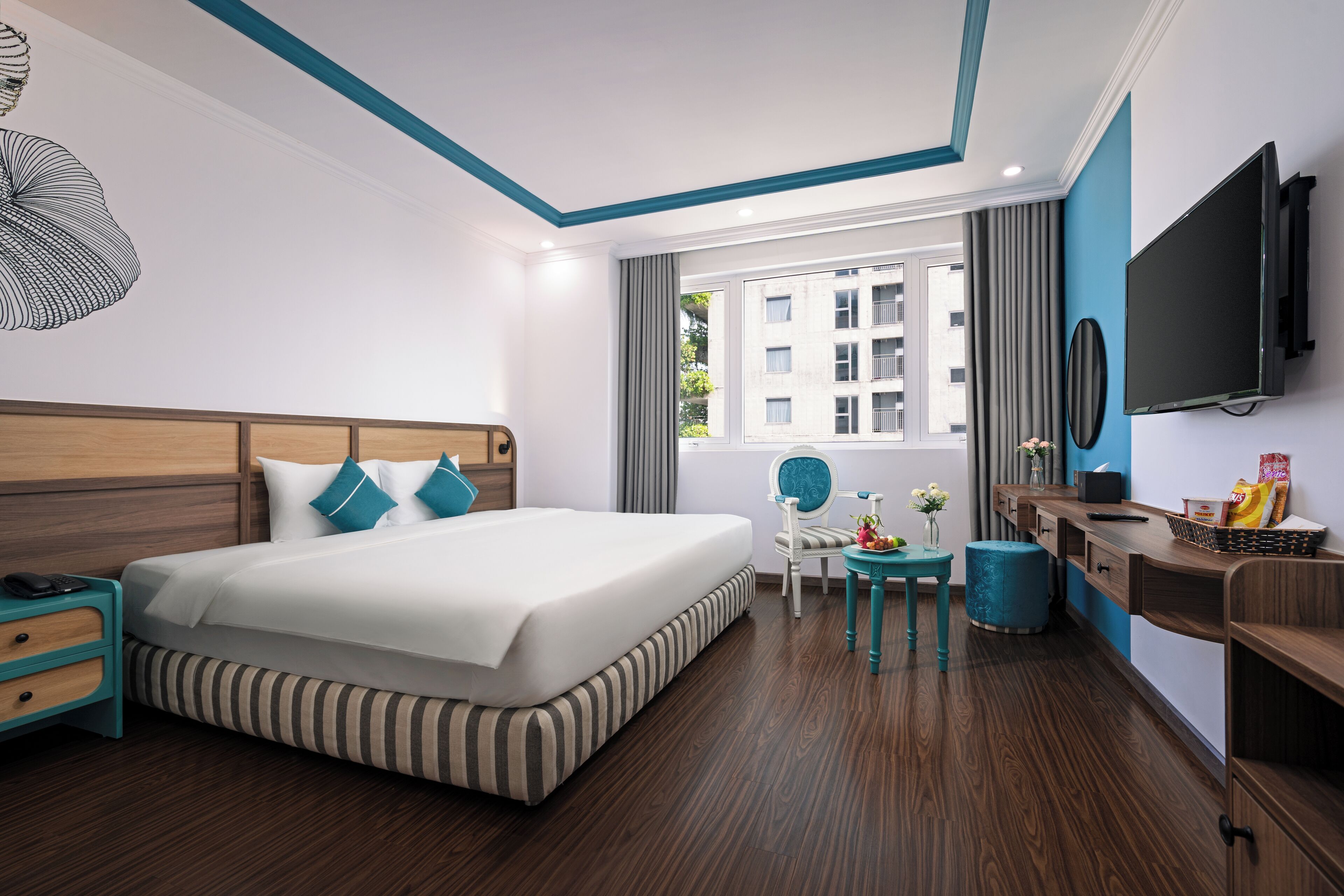 A hotel room with a large bed, a desk with a chair, a TV, and a window with curtains.