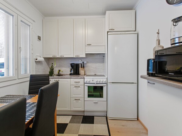 Una cocina compacta con armarios blancos, un refrigerador, una estufa y un microondas.