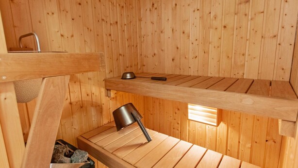 Un sauna en bois avec un banc, une petite table et une chaise.