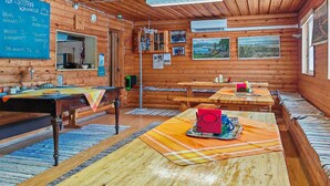 Une charmante cabane en bois dotée d’un tableau noir affichant le menu du petit-déjeuner, d’une table à manger en bois, de bancs et d’une grande fenêtre.