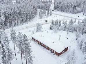Un bâtiment recouvert de neige, doté d’un toit plat, et entouré d’une forêt dense.