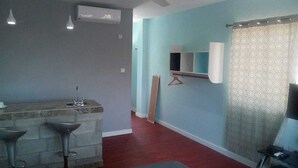 A kitchen with a marble countertop, two bar stools, a hanging light fixture, and a window with a patterned curtain.