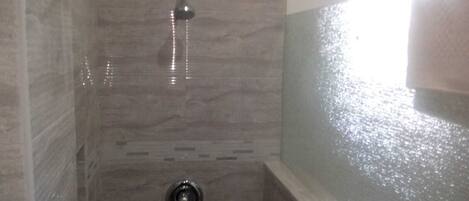 A bathroom with a shower, tiled walls, and a bathtub.