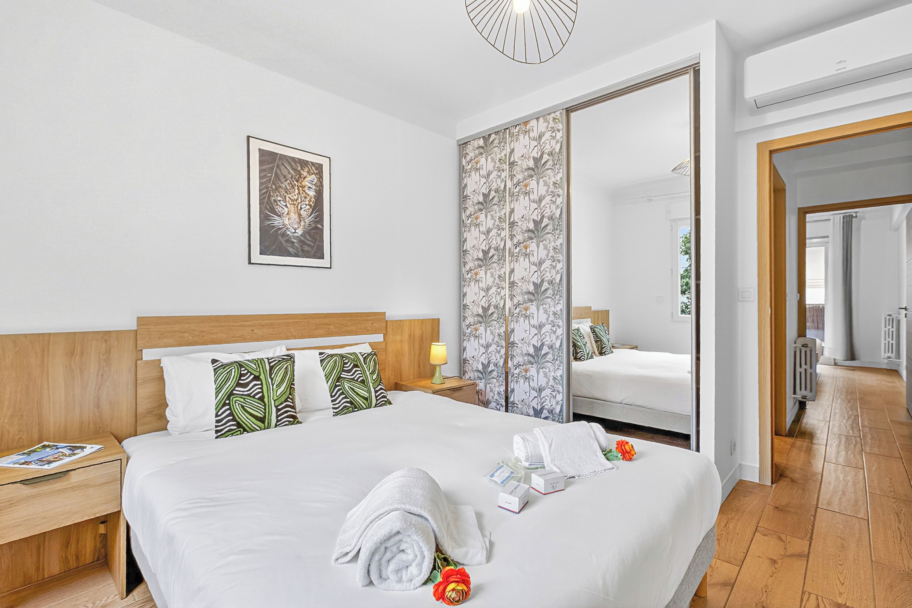 Ein Hotelzimmer mit einem Bett, einem Nachttisch, einem Spiegel und einer Tür zu einem anderen Raum.