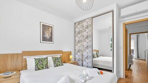 Ein Hotelzimmer mit einem Bett, einem Nachttisch, einem Spiegel und einer Tür zu einem anderen Raum.