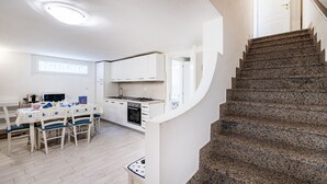 Eine kleine Küche mit weißen Schränken, einem Esstisch mit Stühlen und einer Granit-Wendeltreppe.