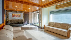 A spacious living area with a wooden ceiling, a fireplace, and a large window. - Treebo Eeshan Rodhi Resort, Darjeeling (Darjeeling)