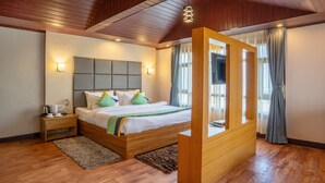 A modern hotel room with a wooden headboard, a large bed, a wooden side table, and a TV mounted on the wall. - Treebo Eeshan Rodhi Resort, Darjeeling (Darjeeling)