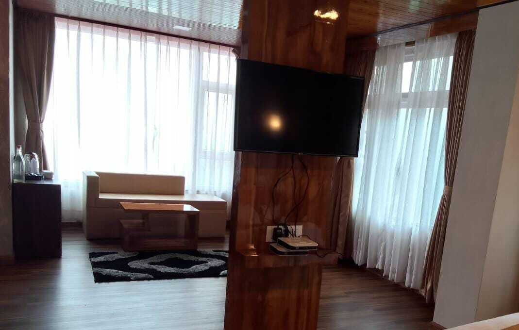 A modern living room with a flat-screen TV mounted on a wooden wall, a sofa, a coffee table, and a rug.