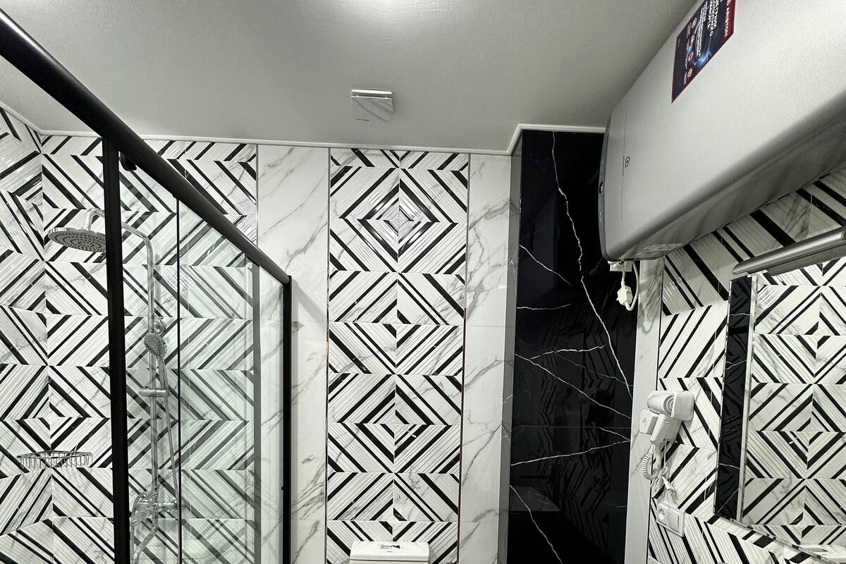 A modern bathroom with a glass shower enclosure, a toilet, and a sink.