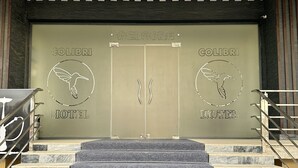 A hotel entrance with a double door, a staircase leading up, and a logo of a bird on the doors. - Colibri Hotel  (Bukhara)