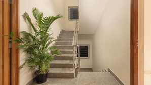 Un escalier avec une rampe en métal, un pot de fleurs et une fenêtre grillagée.