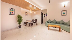 Un salon moderne comprenant un coin repas, un canapé vert, une table basse en bois et une plante en pot.
