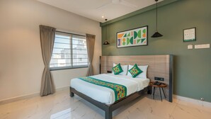 Une chambre d’hôtel avec un grand lit, une fenêtre avec des rideaux, un ventilateur de plafond et une œuvre d’art accrochée au mur.